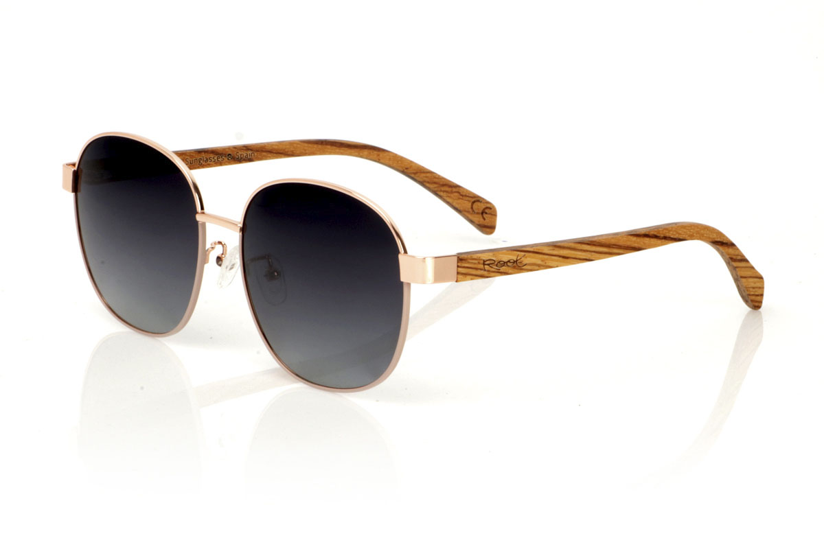 Gafas de Madera Natural de Zebrano CHLOE. Las gafas de sol CHLOE son la definición de versatilidad y estilo atemporal. Este modelo unisex fusiona una montura metálica fina en color bronce, evocando un toque vintage, con varillas de madera de zebra que añaden un contraste natural y moderno. La combinación resulta en unas gafas que se adaptan tanto a looks clásicos como contemporáneos, perfectas para cualquier persona que aprecie la elegancia y la calidad. Con una medida de 156x54mm y un calibre de 58, las CHLOE ofrecen un ajuste cómodo y amplia protección visual. Prepárate para destacar con este diseño único, que promete convertirse en un imprescindible en tu colección Venta al Por Mayor y Detalle | Root Sunglasses® 